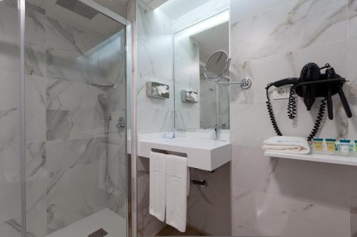 a bathroom with a shower and a sink and a phone at Senator Barajas in Madrid