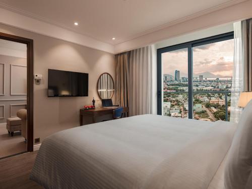Una habitación de hotel con una cama grande y una ventana. en Altara Suites Da Nang by AHG, en Da Nang