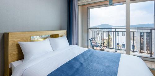 a bedroom with a bed and a large window at Happiness Pension in Jeju
