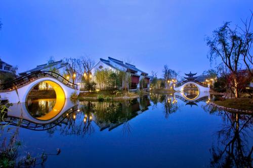 - une vue sur un étang de nuit avec des bâtiments dans l'établissement Banyan Tree Hangzhou, à Hangzhou