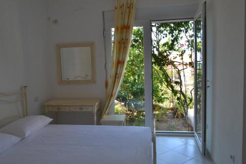 een slaapkamer met een bed en een glazen schuifdeur bij Vila 15 Bougainville in Sarandë