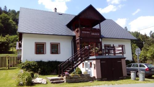 a large white house with a black roof at Penzion Edelštejn in Petrovice