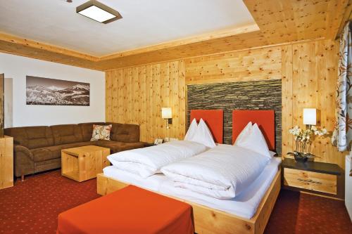 a bedroom with a large bed and a couch at Landhotel Alpenhof Filzmoos in Filzmoos