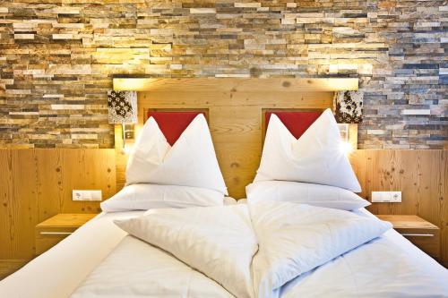 a bedroom with two beds with white pillows at Landhotel Alpenhof Filzmoos in Filzmoos
