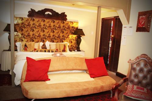 a bedroom with a bed and a couch with red pillows at Victoria Manor in Upington