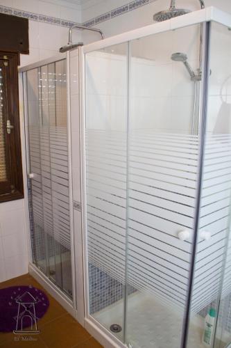 a glass shower enclosure with white blinds in a bathroom at Finca El Molino in Ajofrín
