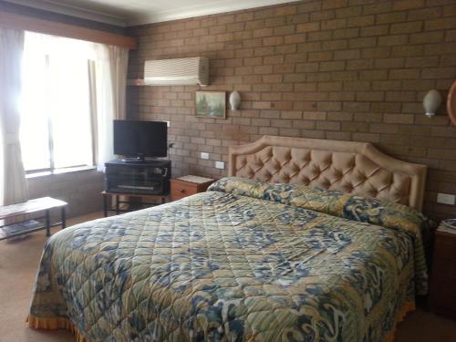 a bedroom with a bed and a tv at Beachview Motel - Adults Only in Bermagui