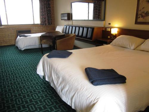 a hotel room with two beds and a table at Canberra Lyneham Motor Inn in Canberra