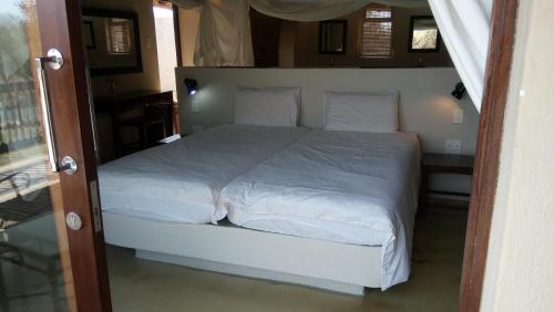 un letto con lenzuola e cuscini bianchi in una camera da letto di Beautiful Mountain Views From A 2-Bedroom Home With Pool a Hoedspruit