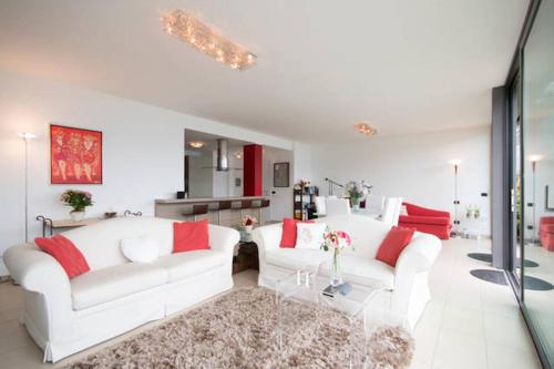 un soggiorno con 2 divani bianchi e cuscini rossi di Parco San Andrea Elegante a Menaggio