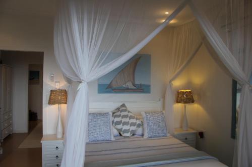 a bedroom with a canopy bed with two lamps at Campismo Ninho 40 in Ponta Malangane