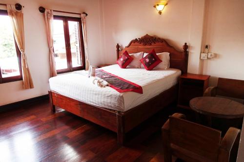 a bedroom with a bed with white sheets and red pillows at Villa Rattanakon in Luang Prabang