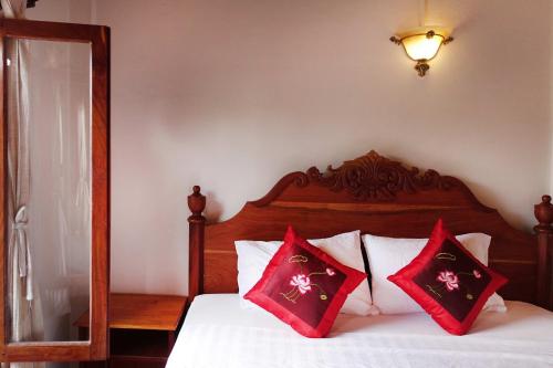 a bedroom with a bed with red pillows on it at Villa Rattanakon in Luang Prabang