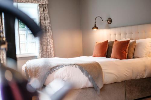 a bedroom with a large bed with orange pillows at The Princess Royal in Farnham