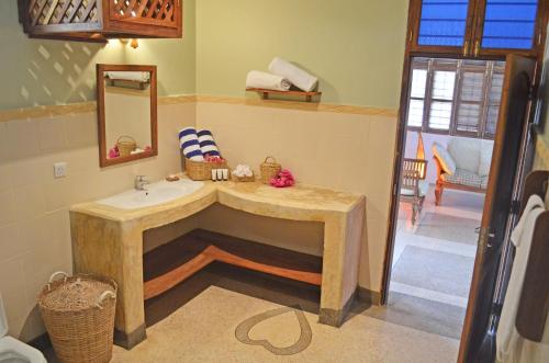 een badkamer met een wastafel en een spiegel bij Alibi's Well in Jambiani