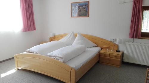 a wooden bed with white pillows on top of it at Reschnerhof in Resia