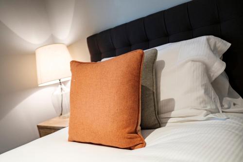 an orange pillow sitting on top of a bed at The Princess Royal in Farnham