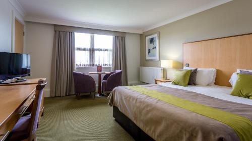 a hotel room with a bed and a flat screen tv at Hellaby Hall Hotel; BW Signature Collection in Hellaby