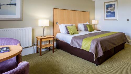 a hotel room with a large bed and a chair at Hellaby Hall Hotel; BW Signature Collection in Hellaby