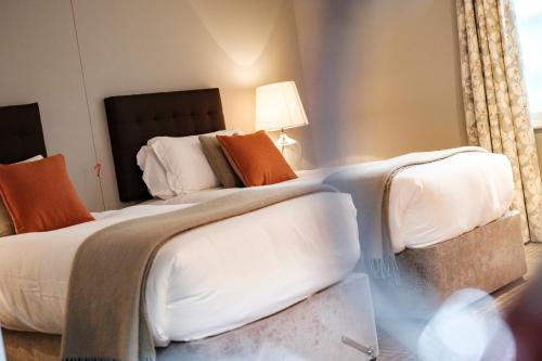 a bedroom with a large bed with white sheets and orange pillows at The Princess Royal in Farnham