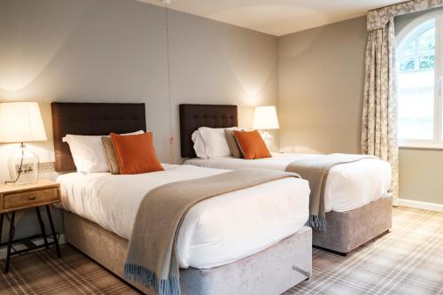 two beds in a room with two lamps and a window at The Princess Royal in Farnham