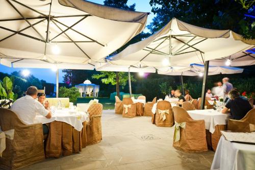 un gruppo di persone seduti ai tavoli sotto gli ombrelloni di Ca' delle Rose a Castelfranco Veneto