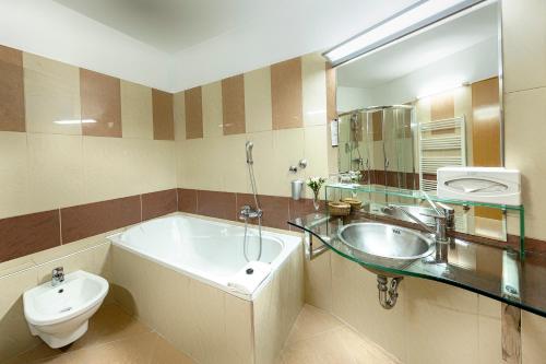 a bathroom with a tub and a sink and a toilet at MenDan Magic Spa & Wellness Hotel in Zalakaros