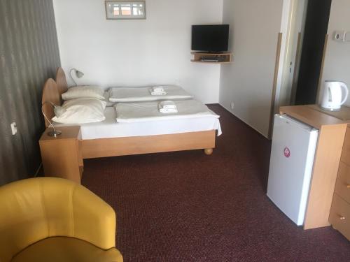 1 dormitorio pequeño con 1 cama y 1 silla amarilla en Hotel City en Pardubice