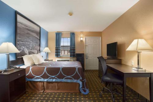 a hotel room with a bed and a desk at Super 8 by Wyndham Henryetta in Henryetta
