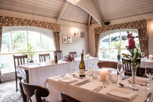 a dining room with white tables and chairs and windows at The Princess Royal in Farnham