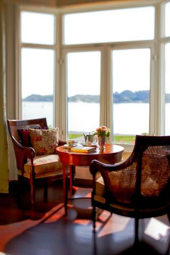 a living room with a table and chairs and windows at Hotel Wassilioff - Unike Hoteller in Stavern
