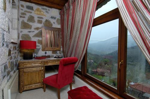 a room with a red chair and a desk and a window at Emotions Country Resort in Voútiron