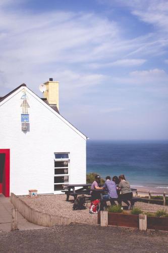 a group of people sitting at a picnic table next to a church at White Park Bay Youth Hostel in Ballintoy
