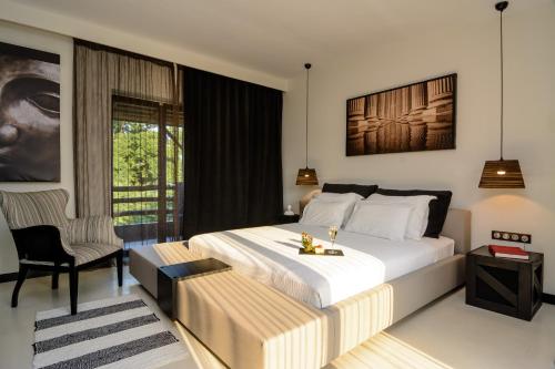 a hotel room with a bed, chair, table and window at Dion Palace Resort and Spa in Limani Litochorou