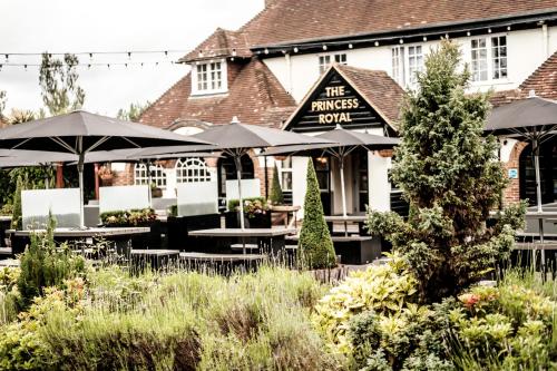a restaurant with tables and umbrellas in front of a building at The Princess Royal in Farnham
