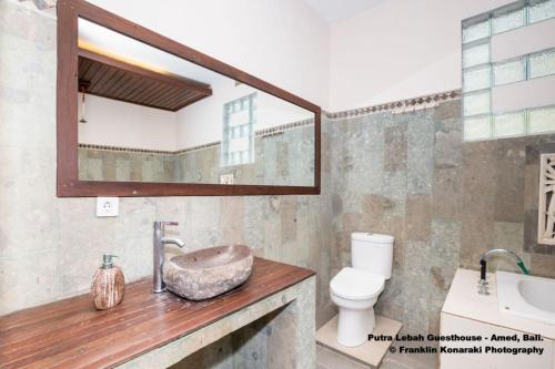 y baño con lavabo, aseo y espejo. en Putra'Lebah Amed Guest House, en Amed