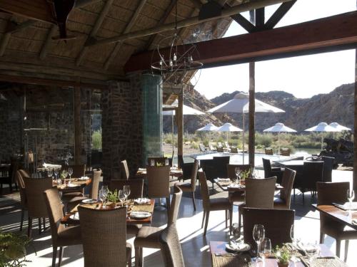 a restaurant with tables and chairs with mountains in the background at Tutwa Desert Lodge in Augrabies