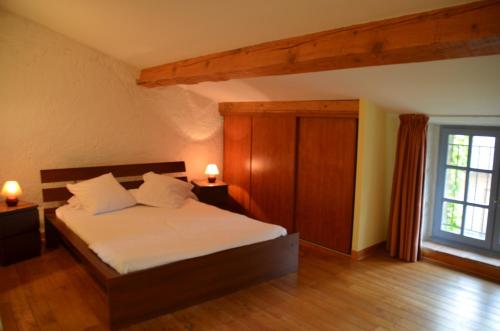 a bedroom with a bed with white sheets and a window at Les Roses d'Autan in Auriac-sur-Vendinelle