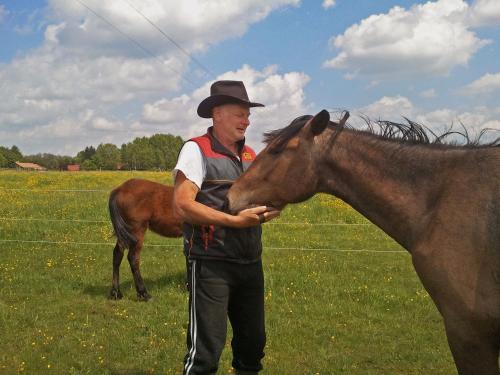 a man in a hat is petting a horse at Kerca Bio Farm in Kercaszomor