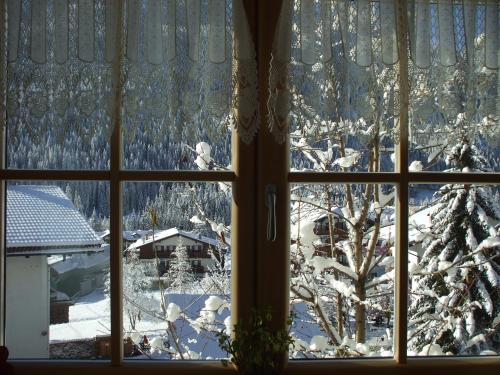 una ventana con vistas a un patio cubierto de nieve en La Campagnola en Canazei