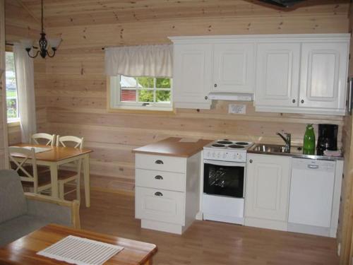 a kitchen with white appliances and a wooden wall at Røldal Hyttegrend & Camping in Røldal