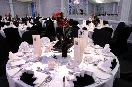 a dining room with tables with white linens and flowers on it at Best Western Plus Dunfermline Crossford Keavil House Hotel in Dunfermline