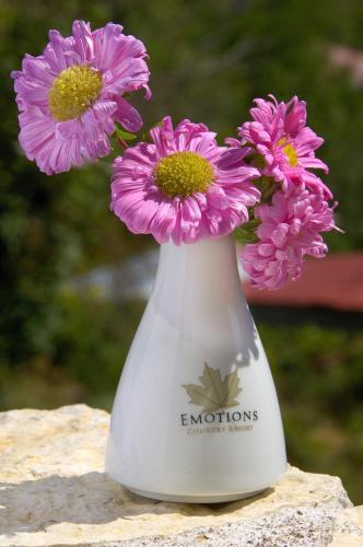 a white vase with pink flowers in it at Emotions Country Resort in Voútiron