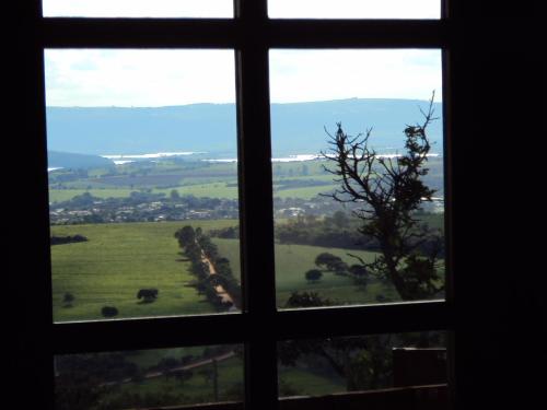 a window with a view of a green field seen through it at Pousada Encantos do Cerrado in Delfinópolis