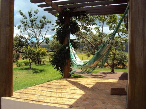 a hammock in a porch with a view of a field at Pousada Encantos do Cerrado in Delfinópolis