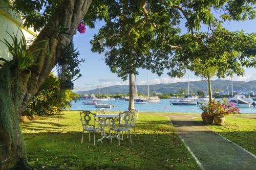 a table and chairs sitting on the grass near the water at One Love Cozy Studio Seawind On The Bay in Montego Bay