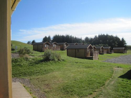 a row of wooden huts in a grass field at Höfn Cottages in Höfn