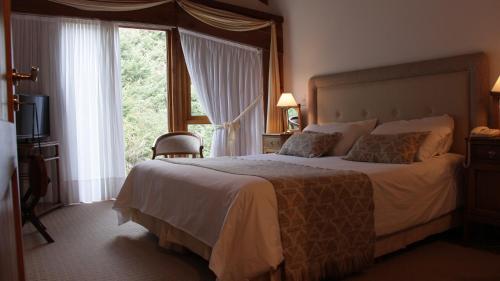 a bedroom with a large bed with a large window at Aldea Bonita in Villa La Angostura
