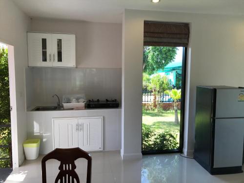 a kitchen with a refrigerator and a table and a chair at Saree Lagoon Villa Koh Samui in Lipa Noi
