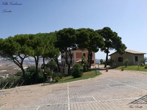a parking lot in front of a house with trees at Relais Villa Giuliana in Licata
